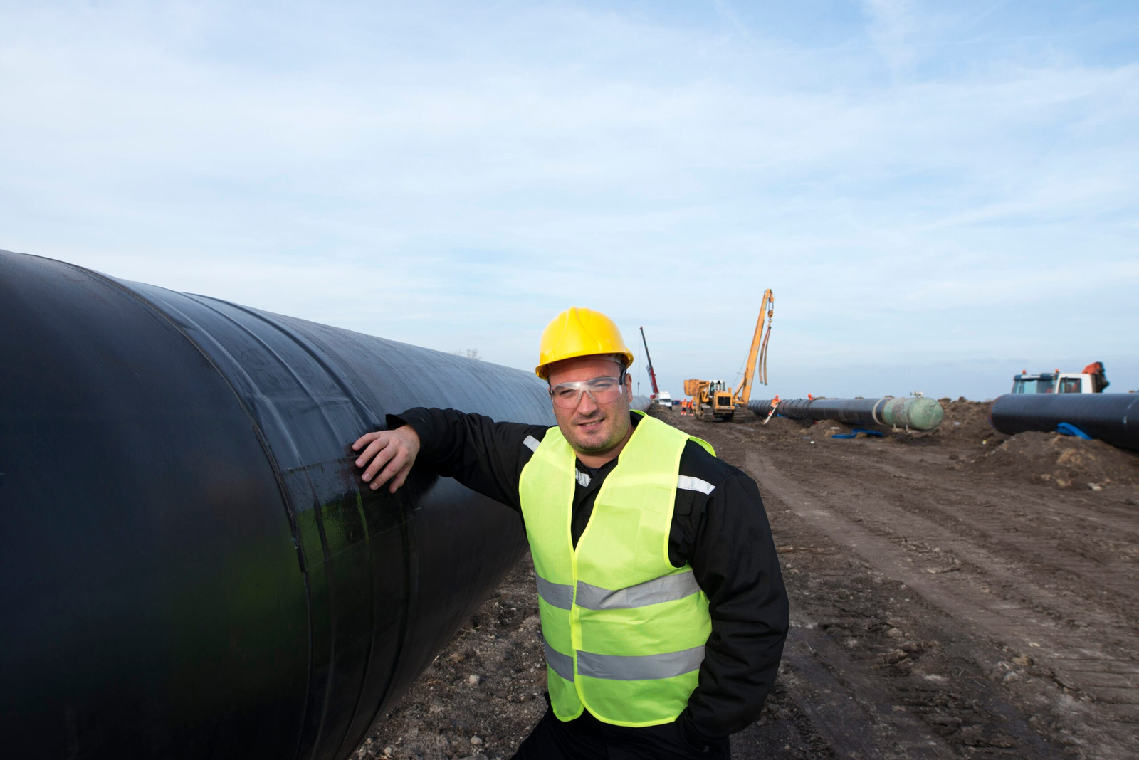 portrait oilfield worker standing by gas pipe construction site scaled