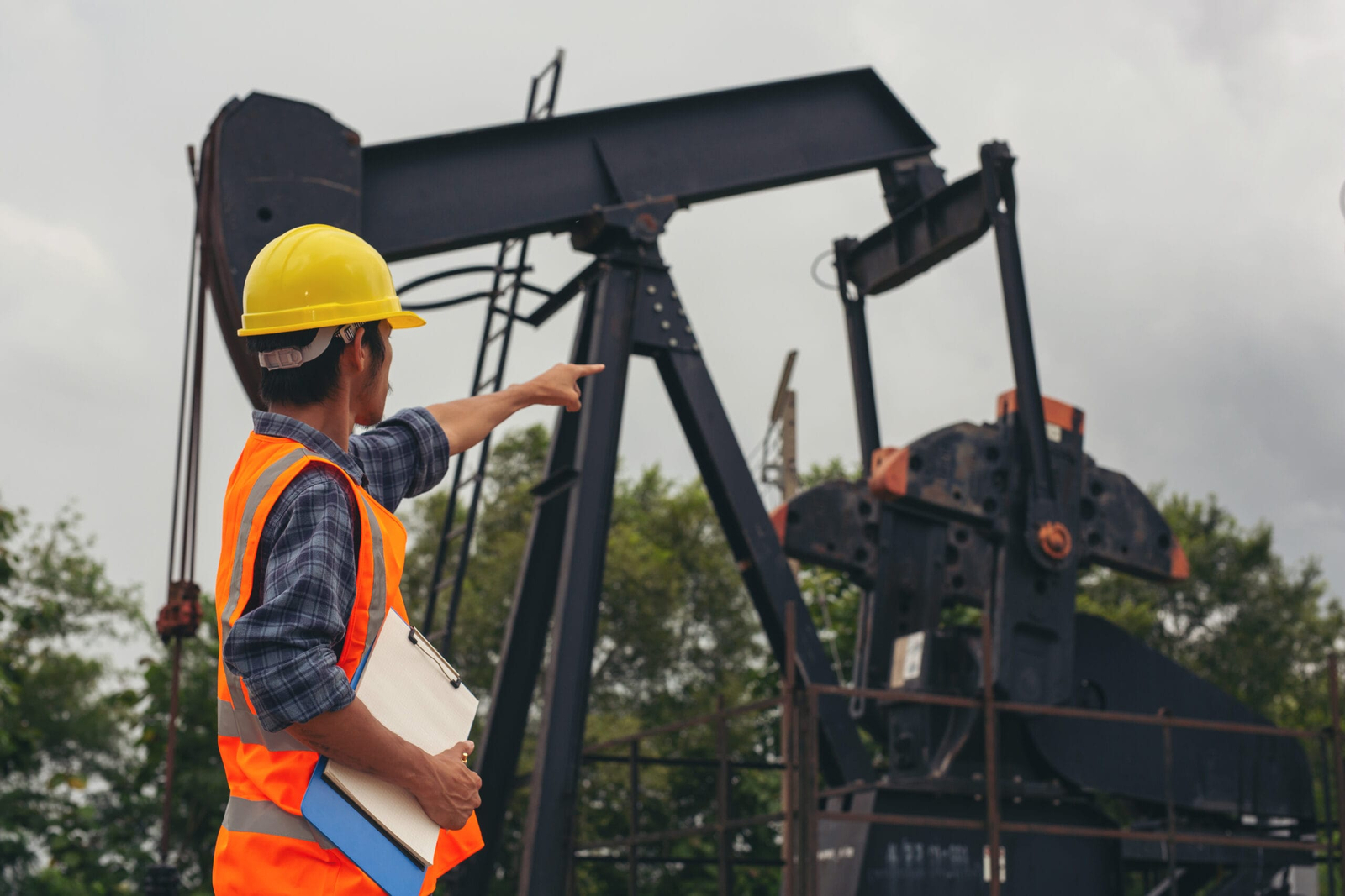 workers standing checking beside working oil pumps scaled